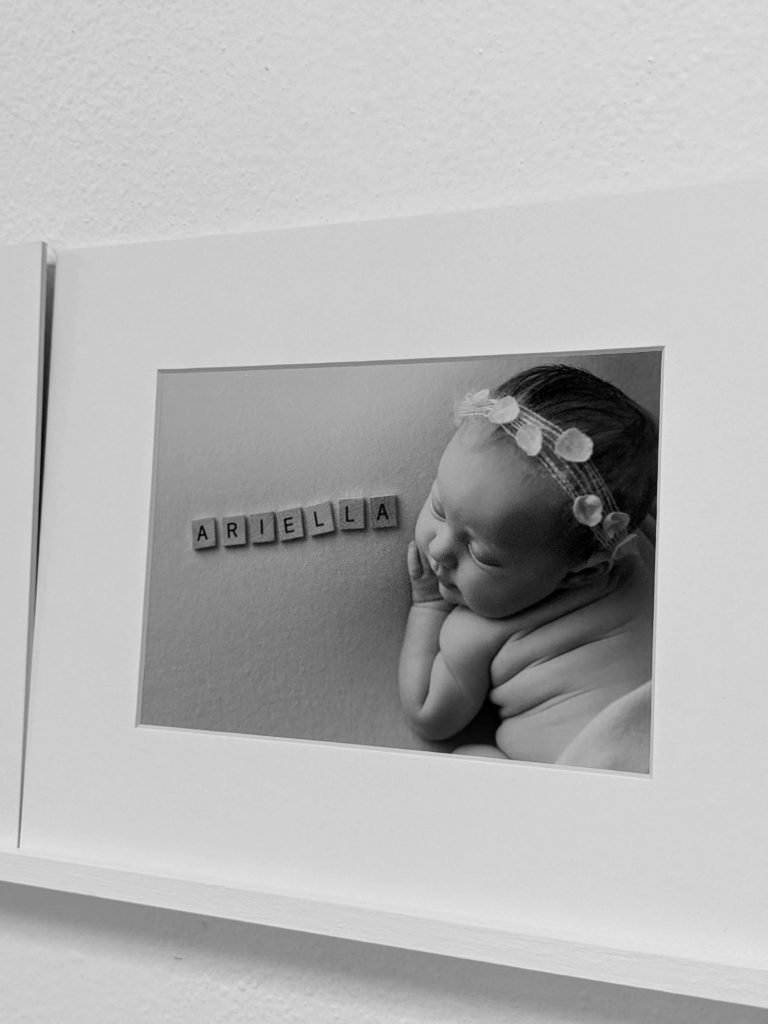 Image of newborn baby girl with name spelled out with scrabble letters,  framed and displayed on a shelf