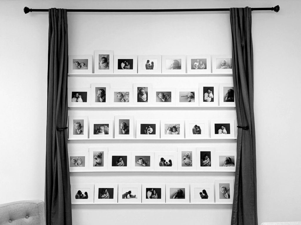 Image of reveal wall displaying framed images on shelves on the wall. 
