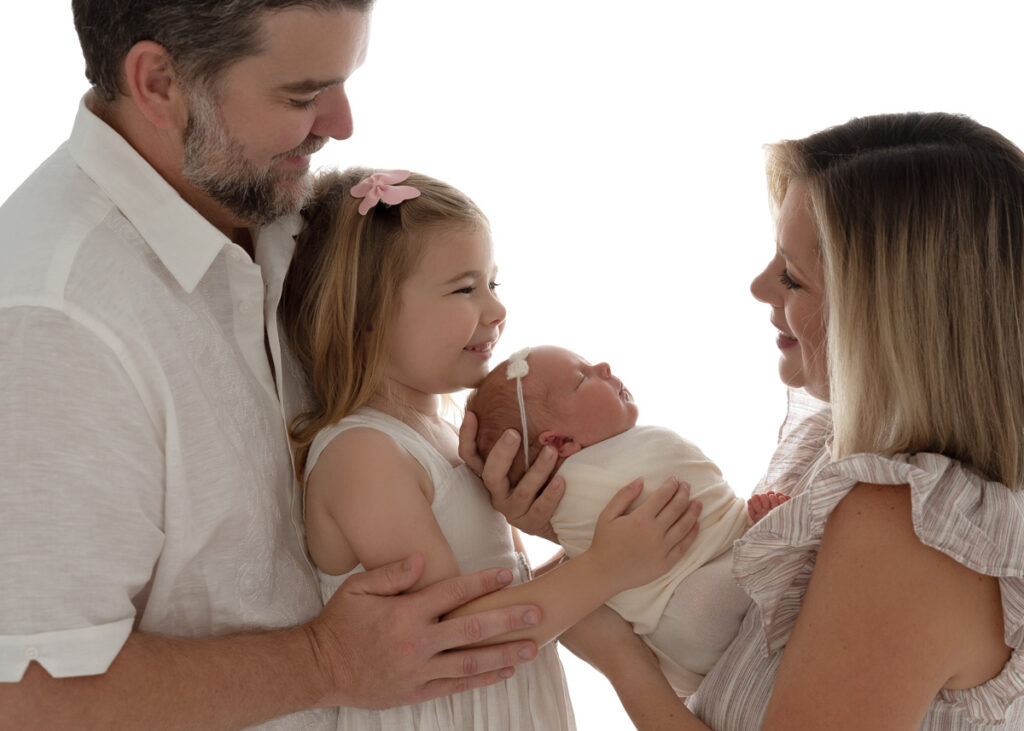 Backlit profile image of family of 4 holding newborn baby girl