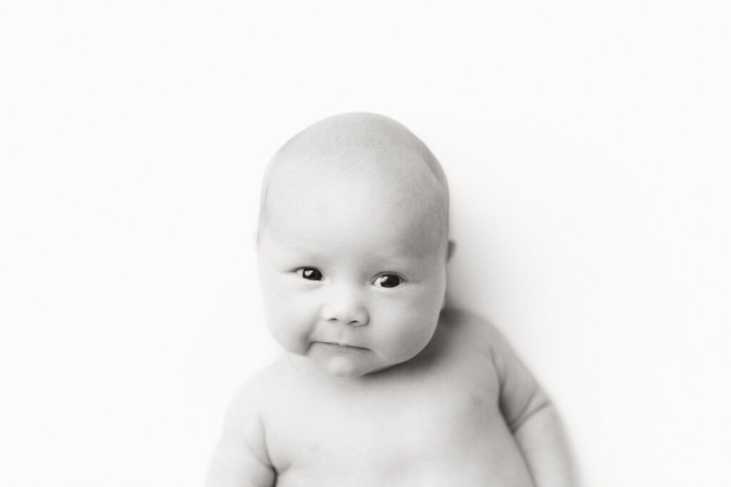 Foley, AL Newborn Photographer black and white mugshot image of baby during posed newborn studio session.
