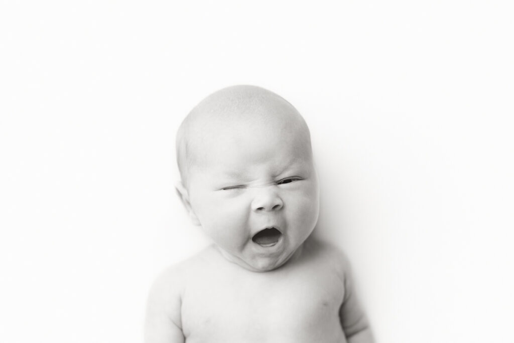 Mobile, AL Newborn Photographer black and white mugshot image of baby during posed newborn studio session.