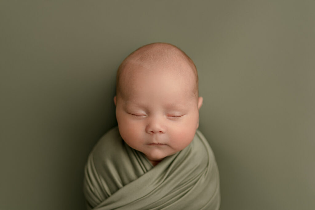 Pensacola, FL Newborn Photographer baby swaddled in green during studio session.