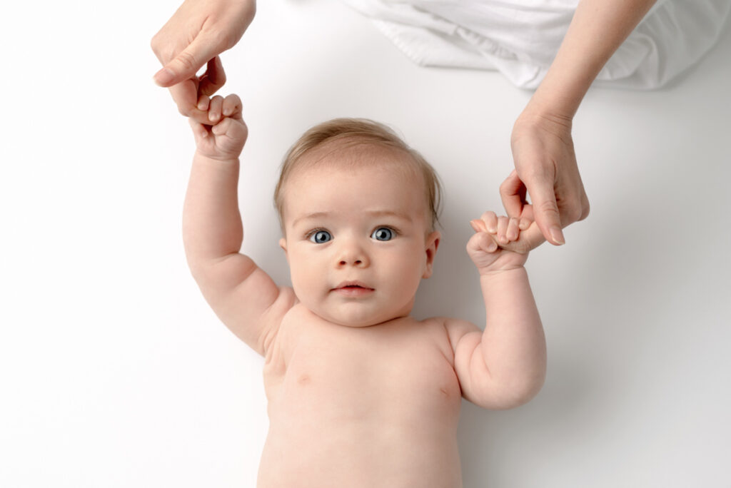 Image of 4 month old baby holding onto his mothers fingers.