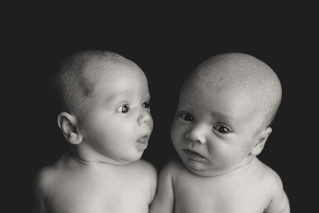 Gulf Breeze, FL newborn photographer.  Black and white image of baby boy twins awake and making funny faces during a studio session.