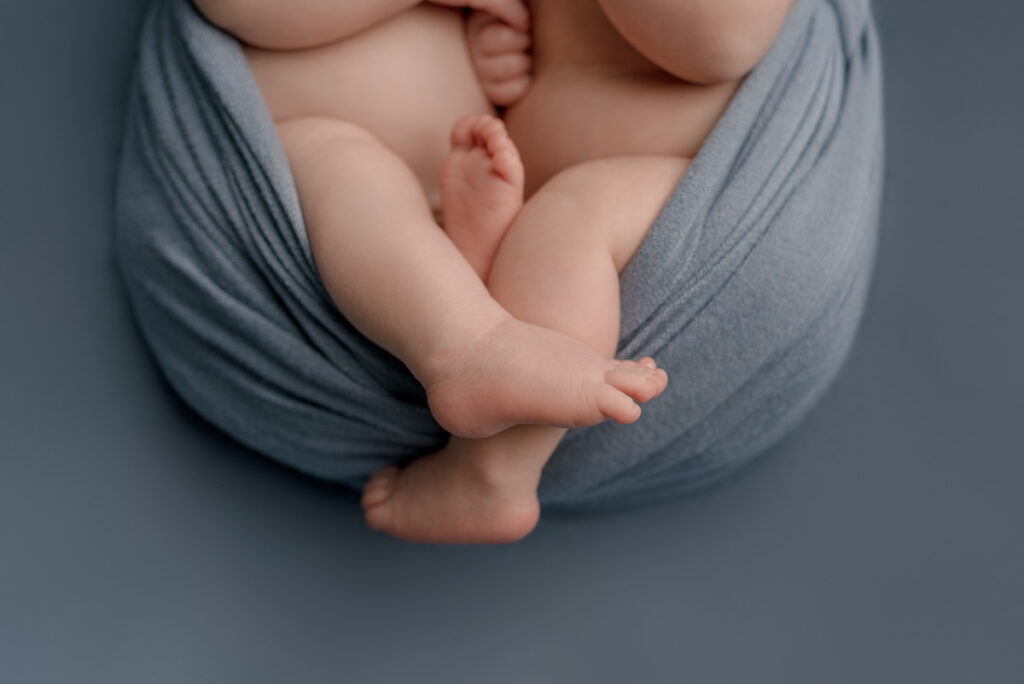 Navarre, FL newborn photographer.  Close up image of baby boy twins feet during a posed studio photography session.