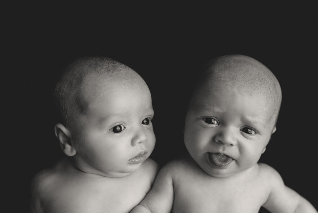 Navarre, FL newborn photographer. Black and white image of baby boy twins awake and making funny faces during a studio session.