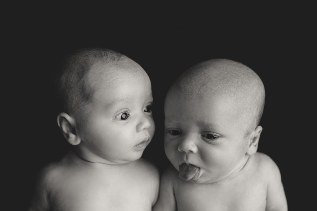 Pace, FL newborn photographer.  Black and white image of baby boy twins awake and making funny faces during a studio session.